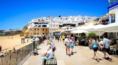 a group of people walking on a sidewalk near a beach at CASA 4 - Perfect location - Sea view by DreamvillasAlbufeira in Albufeira