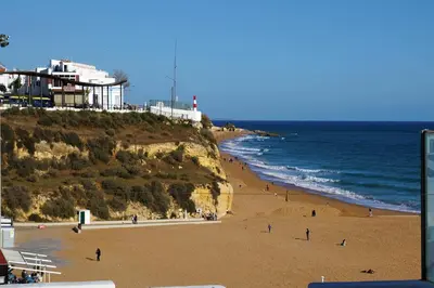 a beach with people on the sand and the ocean at CASA 4 - Perfect location - Sea view by DreamvillasAlbufeira in Albufeira