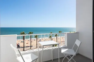 a balcony with a table and chairs and the beach at Maresia - Front beach - Quarteira in Vilamoura