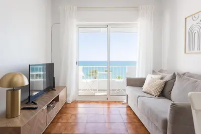 a living room with a couch and a television at Maresia - Front beach - Quarteira in Vilamoura