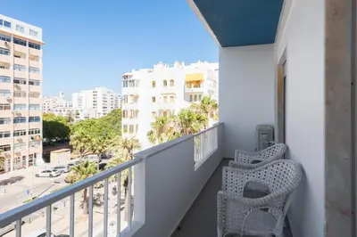a balcony with a chair and a view of a city at Maresia - Front beach - Quarteira in Vilamoura