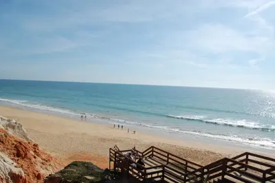 a beach with a fence and people on the beach at Falésia Beach Just 800 m (Apartment Surfal) in Roja- Pé