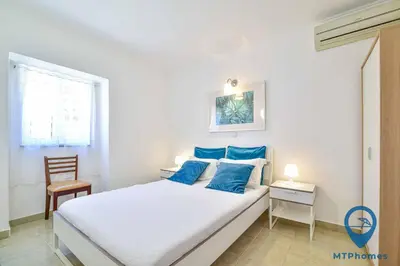 a bedroom with a bed with blue pillows and a chair at Vila Portuguesa by MTPhomes in Albufeira