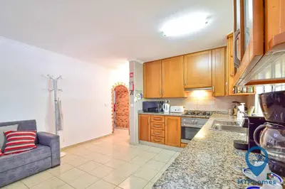 a kitchen with wooden cabinets and a couch in it at Vila Portuguesa by MTPhomes in Albufeira