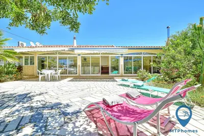 a patio with chairs and tables and a house at Vila Portuguesa by MTPhomes in Albufeira
