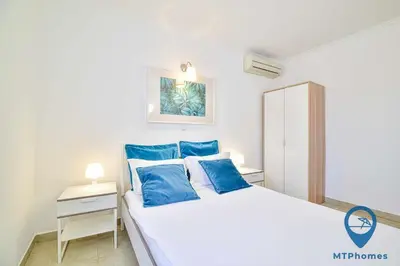 a bedroom with a white bed with blue pillows at Vila Portuguesa by MTPhomes in Albufeira
