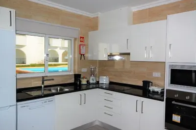 a kitchen with white cabinets and a sink and a window at Apartment MargemSul - Pool - Beach - Free Wifi - Air Con in Albufeira