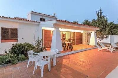 a patio with a table and chairs and a house at Casa das Anas by HelloVacations in Albufeira