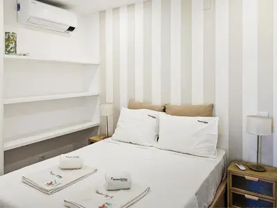 a bedroom with a bed with white sheets and striped walls at FLH Vilamoura Sunny Apartment with Pool in Vilamoura