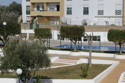 a view of a building with a pool and trees at Apartamento Felicidade in Almancil