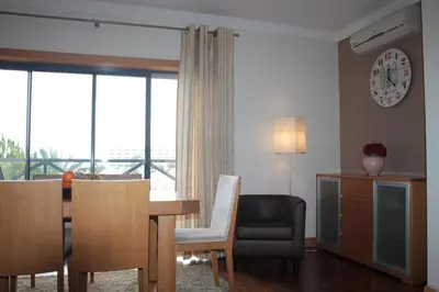 a living room with a table and chairs and a dining room at Apartamento com Piscina em Albufeira, Corcovada in Albufeira