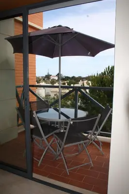 a table and chair with an umbrella on a balcony at Apartamento com Piscina em Albufeira, Corcovada in Albufeira