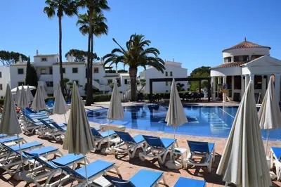 a swimming pool with lounge chairs and umbrellas at Old Village Design 3 Bedroom Townhouse in Vilamoura