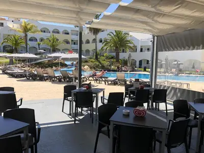 a restaurant with tables and chairs next to a pool at Natura Algarve Club in Albufeira