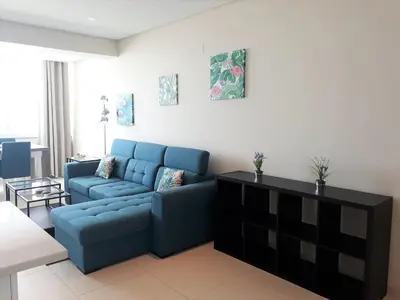 a living room with a blue couch and a table at ABMAR- Por-do-sol, Vista mar, Remodelado, Wifi, 80mt Praia in Quarteira