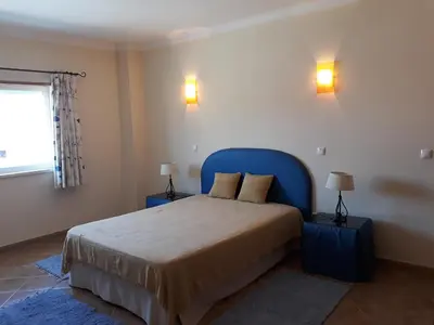a bedroom with a bed with blue headboard and two lamps at AMM Albufeira Nice Hollydays apartment in Albufeira