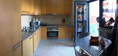 a kitchen with wooden cabinets and a counter top at Apt 2 Quartos, BBQ, AC, Terraço, Prestige For Home in Quarteira