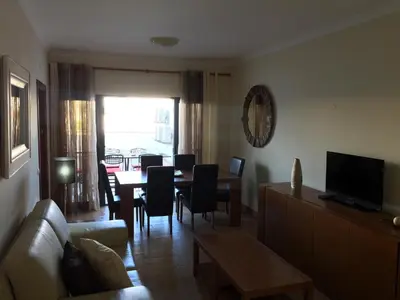 a living room with a couch and a table with chairs at Apt 2 Quartos, BBQ, AC, Terraço, Prestige For Home in Quarteira