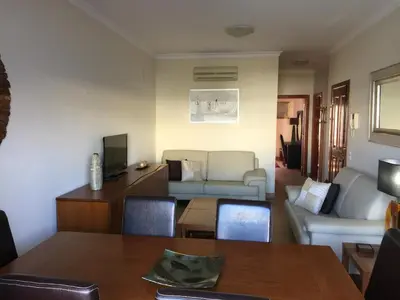 a living room with a table and a couch at Apt 2 Quartos, BBQ, AC, Terraço, Prestige For Home in Quarteira