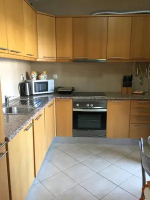 a kitchen with wooden cabinets and a stove and a microwave at Apt 2 Quartos, BBQ, AC, Terraço, Prestige For Home in Quarteira