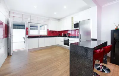 a kitchen with red and white walls and wooden floors at Full private 180sqm Villa - Terrace Jacuzzi - 200m Beach & Sea View in Albufeira