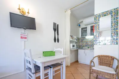 a kitchen with a table and a tv on the wall at Bem Parece by Umbral in Albufeira