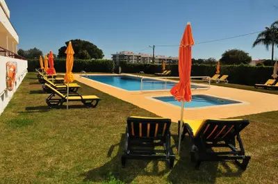 a group of chairs and umbrellas next to a pool at Solgarve in Quarteira