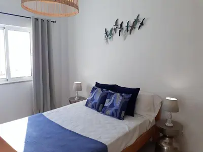 a bedroom with a bed with blue pillows on it at Atlantico 8- Vista Mar, Ar-Condicionado, 80mt Praia, Wifi in Quarteira