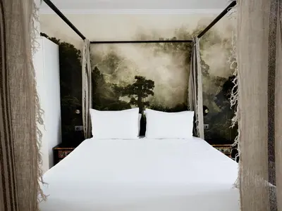 a bed with white pillows in a room with a painting at Casa Apollo Guesthouse in Faro