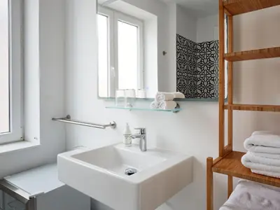 a white bathroom with a sink and a mirror at Casa Apollo Guesthouse in Faro