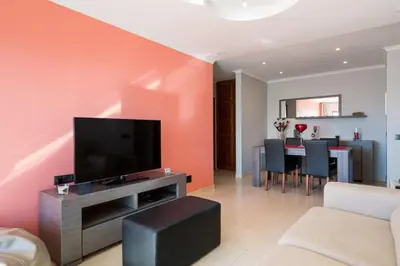 a living room with a television and a table with chairs at Akisol Quarteira Gun in Quarteira