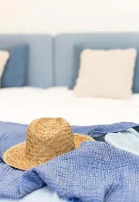 a straw hat sitting on top of a bed at Casa Pé na Areia- Unique Spot- Beach front by DreamvillasAlbufeira in Albufeira