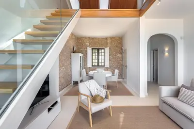 a living room with a staircase and a dining room at Casa Pé na Areia- Unique Spot- Beach front by DreamvillasAlbufeira in Albufeira