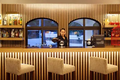 a woman standing behind a bar with two chairs at Sao Rafael Holidays in Albufeira