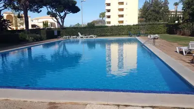 a large blue swimming pool with chairs and a building at Casal das Alfarrobeiras, 7 in Vilamoura