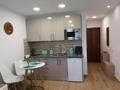 a kitchen with white cabinets and a table and chairs at Lux Home in Albufeira