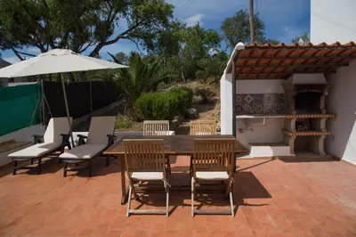 a patio with a table and chairs and an umbrella at CASA GRAZINA in Boliqueime