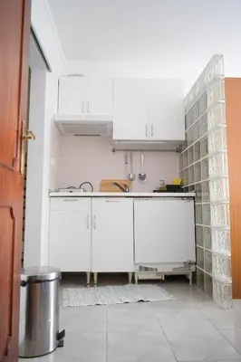 a kitchen with white cabinets and a tile wall at Estúdio-Gambelas in Faro