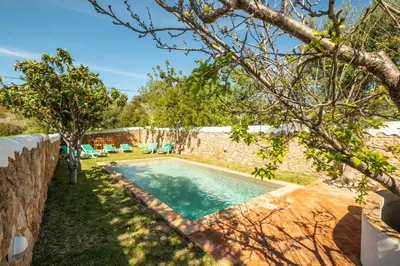a swimming pool in a yard next to a stone wall at Villa Monte Algarvio - Private Heated Pool - wifi in Tunes