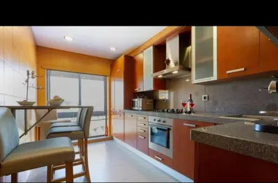 a kitchen with wooden cabinets and a counter top at Parque Atlântico com Vista Mar in Quarteira