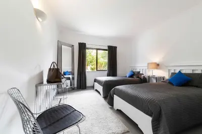 a bedroom with two beds and a chair and a window at Beach Design House Sao Rafael in Albufeira