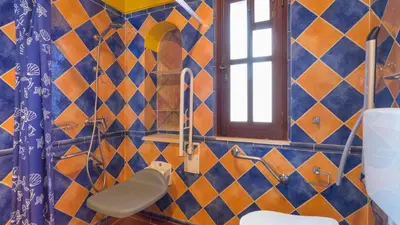 a bathroom with a blue and orange tiled wall at Casinhas Wheelchair friendly in Boliqueime