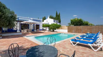 a swimming pool with chairs and a table and a house at Casinhas Wheelchair friendly in Boliqueime