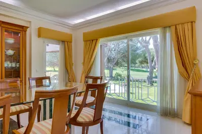 a dining room with a table and chairs and a large window at OnJ Vilamoura in Quarteira