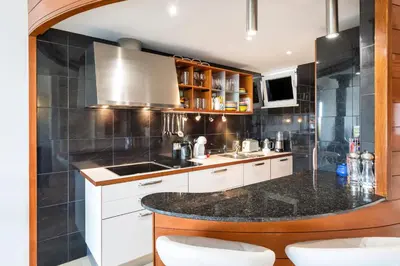 a kitchen with white cabinets and a black counter top at Romy in Vale do Lobo