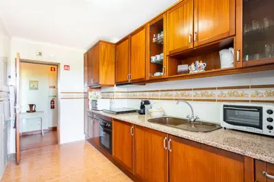 a kitchen with wooden cabinets and a sink at WHome | Vilamoura Sunny Apartment in Quarteira