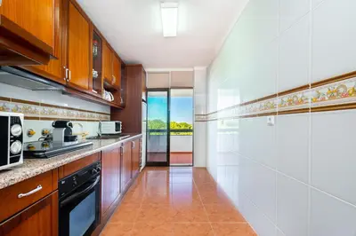 a kitchen with wooden cabinets and a stove top oven at WHome | Vilamoura Sunny Apartment in Quarteira