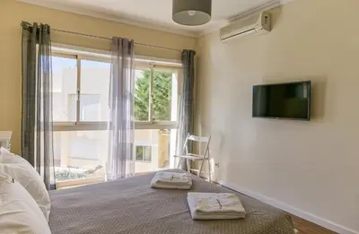a bedroom with a bed with a tv and a window at FLH Falésia Flat with Pool in Vilamoura