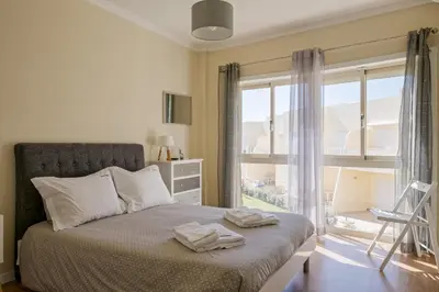 a bedroom with a bed and a large window at FLH Falésia Flat with Pool in Vilamoura