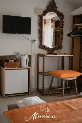 a living room with a mirror and a stool at Guest House Almeixar in Almancil